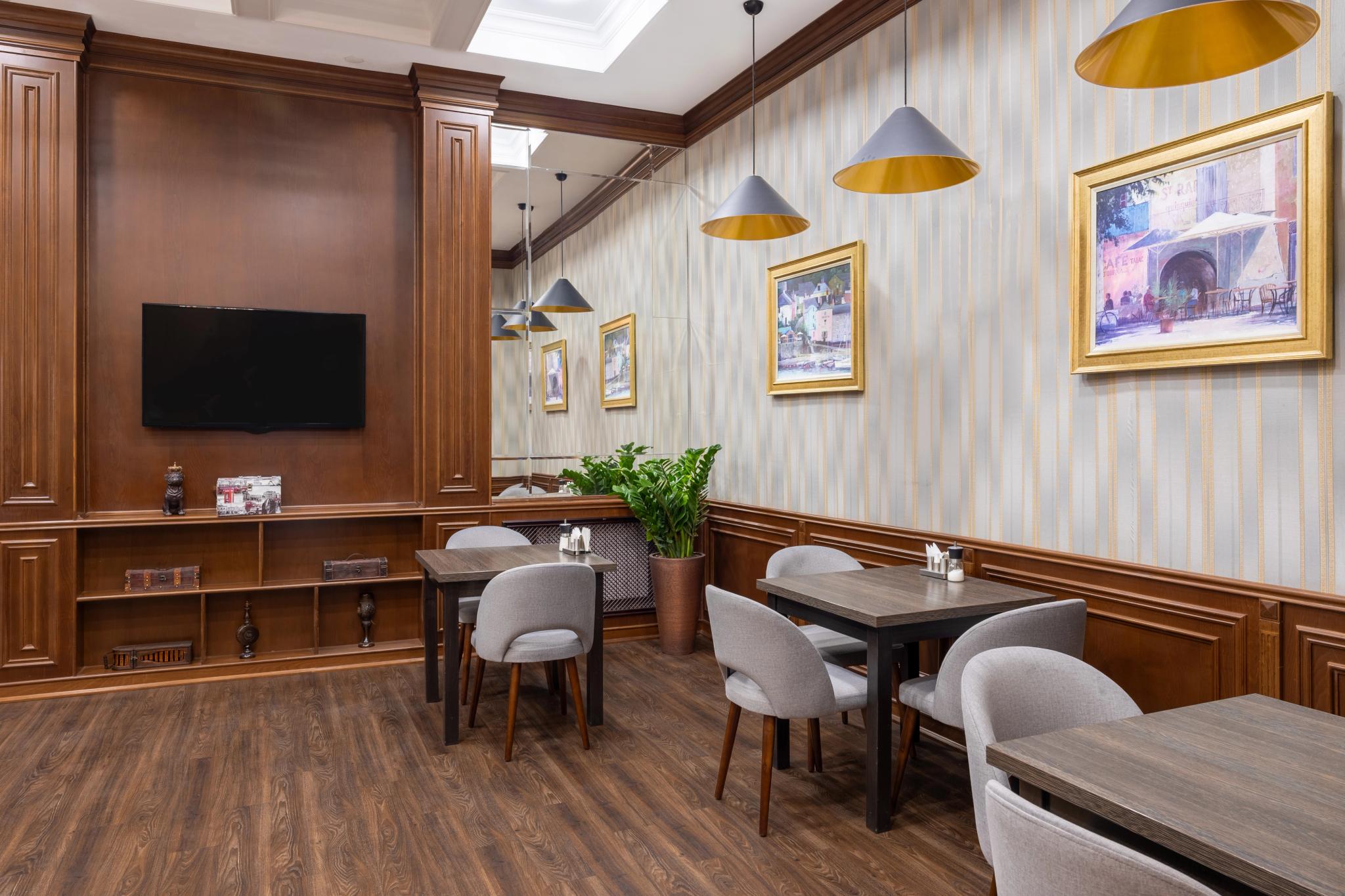 Интерьер зоны завтраков отеля Rush Inn в Астане: деревянная стена с телевизором и полками — интерьерная съёмка
