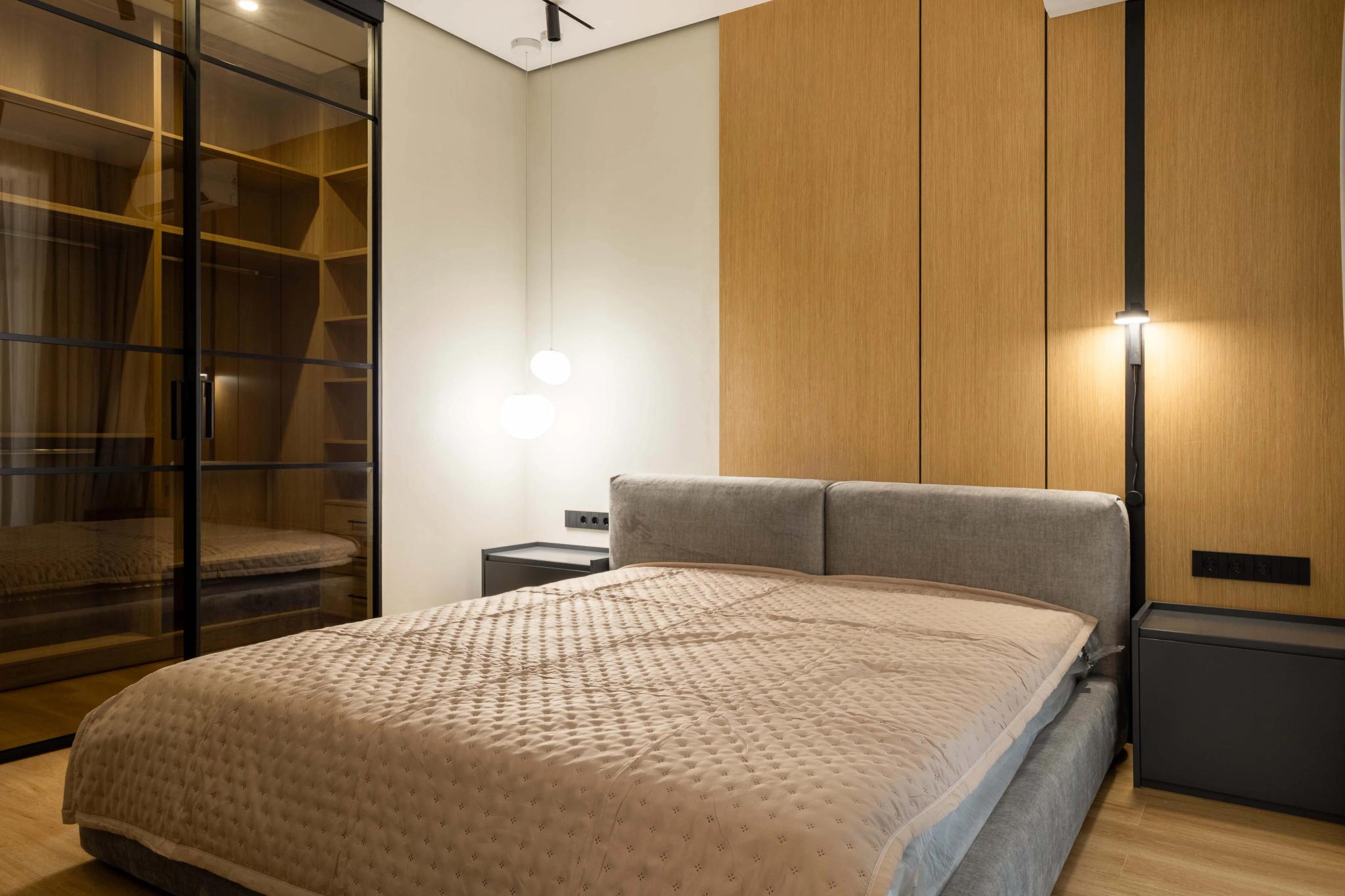 Contemporary bedroom with wooden wall panels and gray upholstered bed - luxury interior photography Kazakhstan