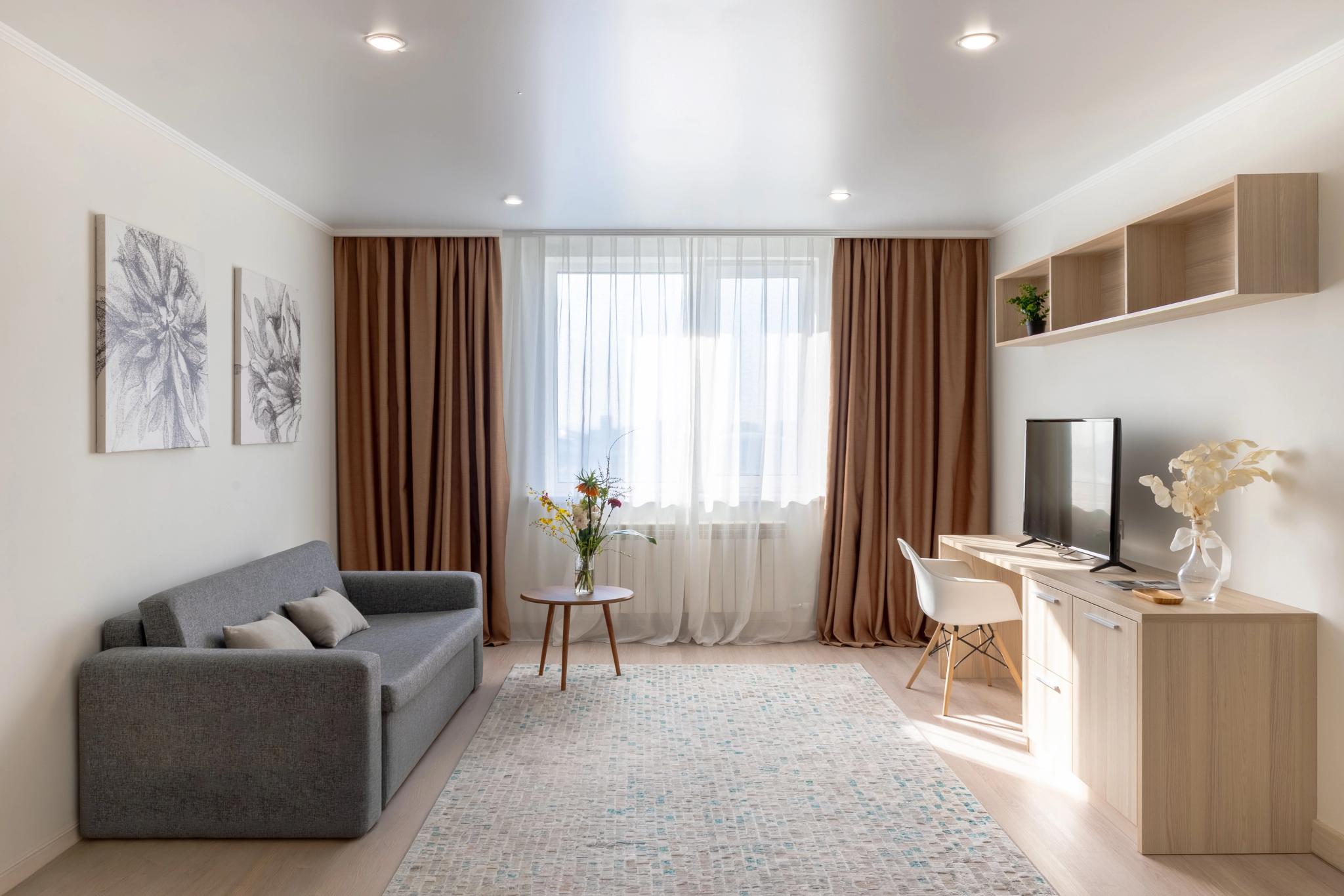 Modern hotel room with grey sofa, wooden furniture and panoramic windows - hotel interior photography Astana by professional photographer