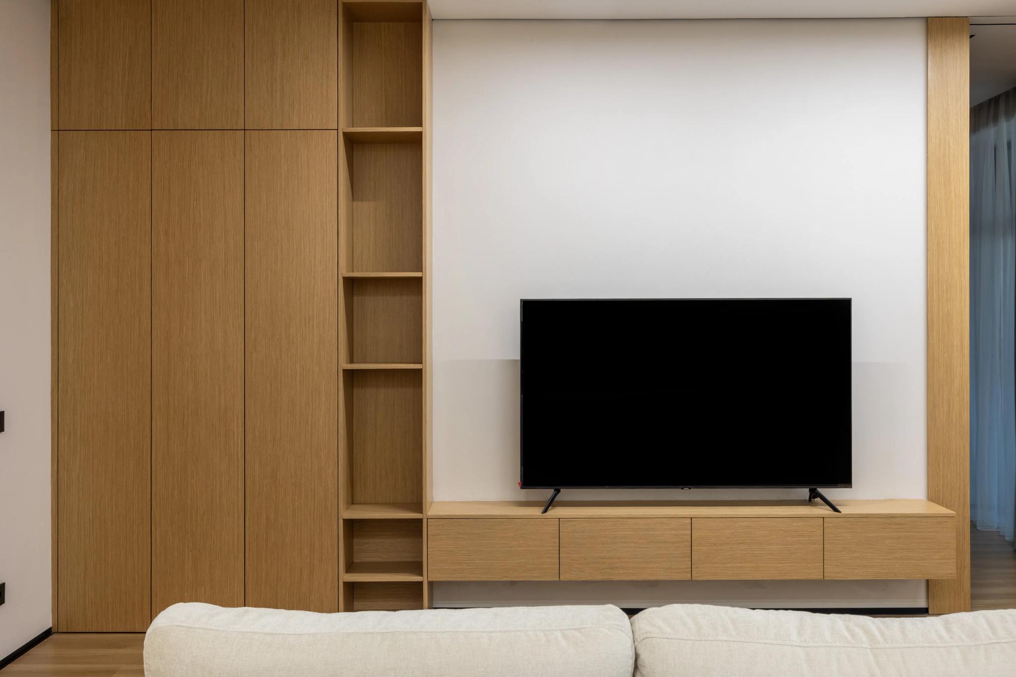 Contemporary living room with wooden wall paneling, built-in TV unit and minimalist sofa — professional interior photography Kazakhstan