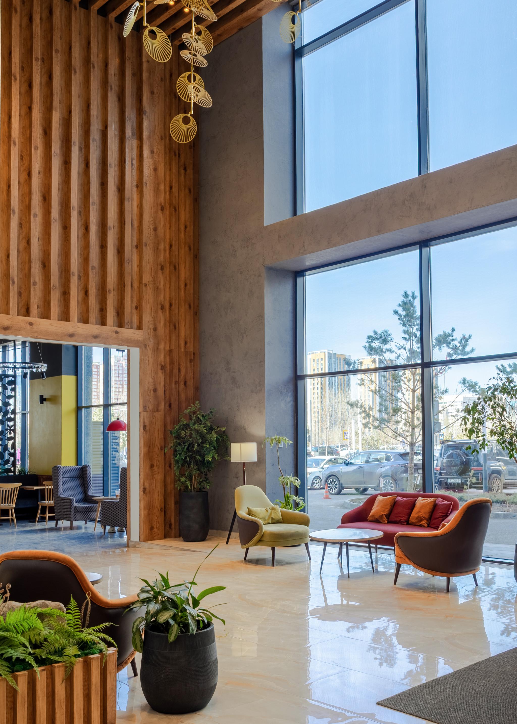 Tor'Re Astana hotel lobby featuring high ceilings, wooden wall panels, and contemporary furniture. Hotel interior photography Kazakhstan