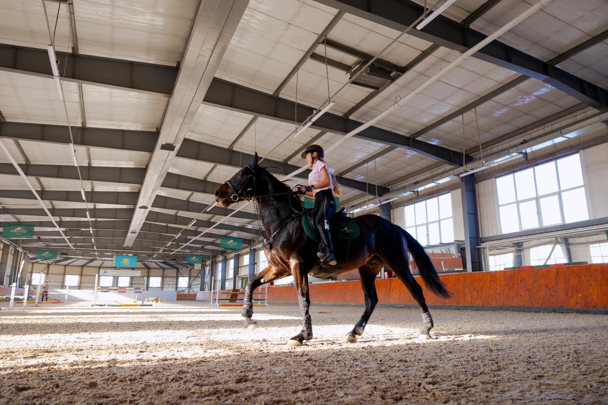 Spacious indoor riding arena at Prestige equestrian club in Astana, featuring modern architectural design and professional architectural photography