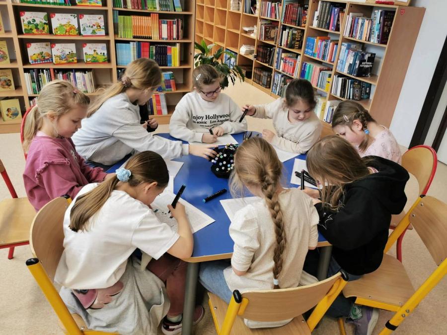 Dziewczynki rozwiązujące quizy czytelnicze w bibliotece.