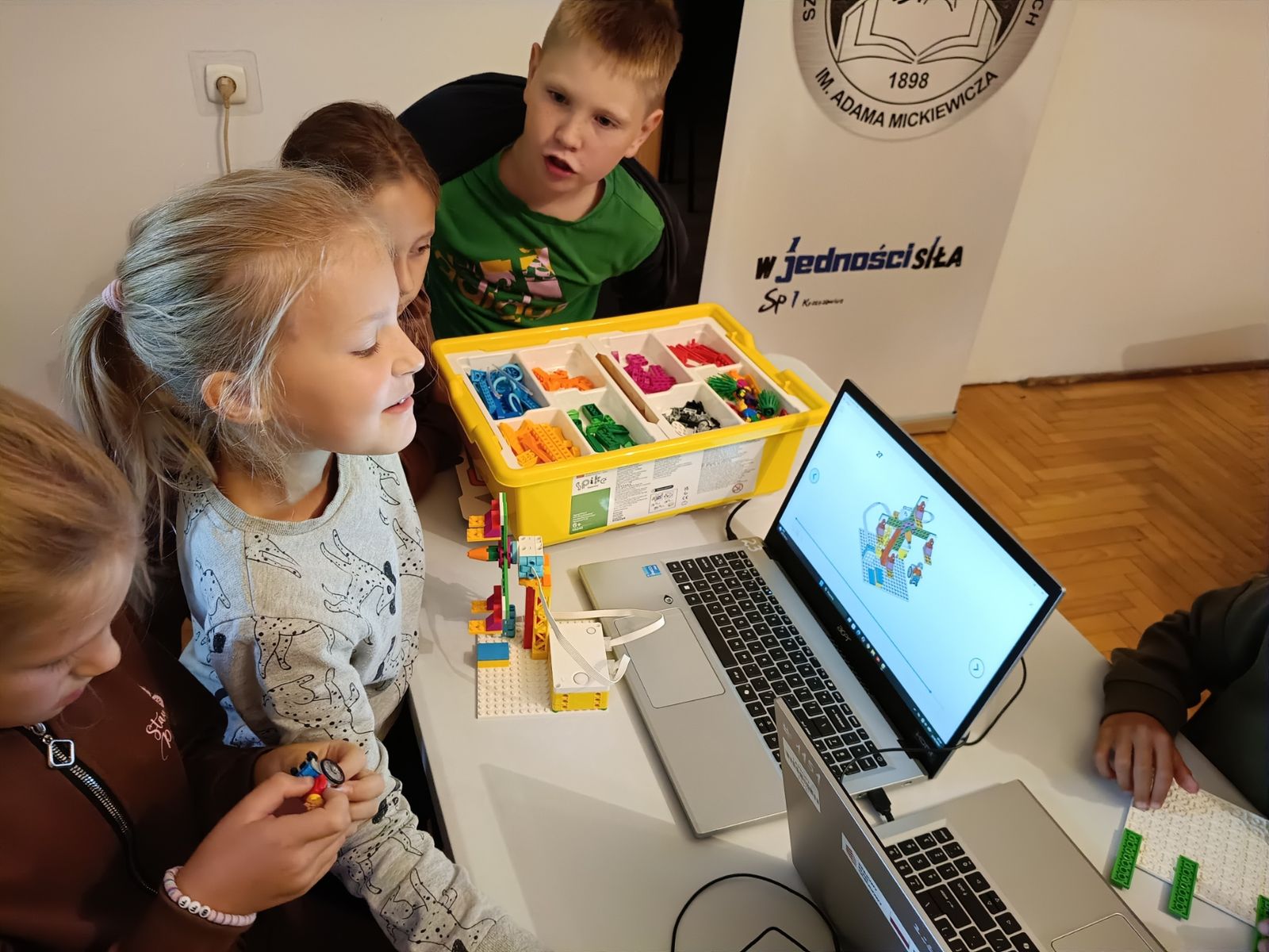 Dziewczynki po zbudowaniu karuzeli z kloców, uruchamiają ją na komputerze