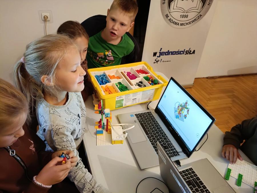 Dziewczynki po zbudowaniu karuzeli z kloców, uruchamiają ją na komputerze
