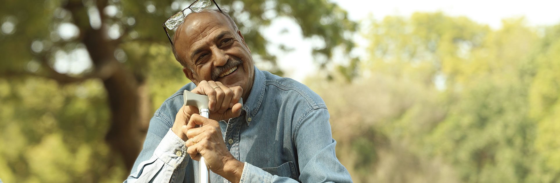 Man smiling, holding a cane while seated. Man smiling, holding a cane while seated.