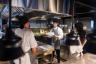 Chef explaining the menu to a group of cooks at a restaurant
