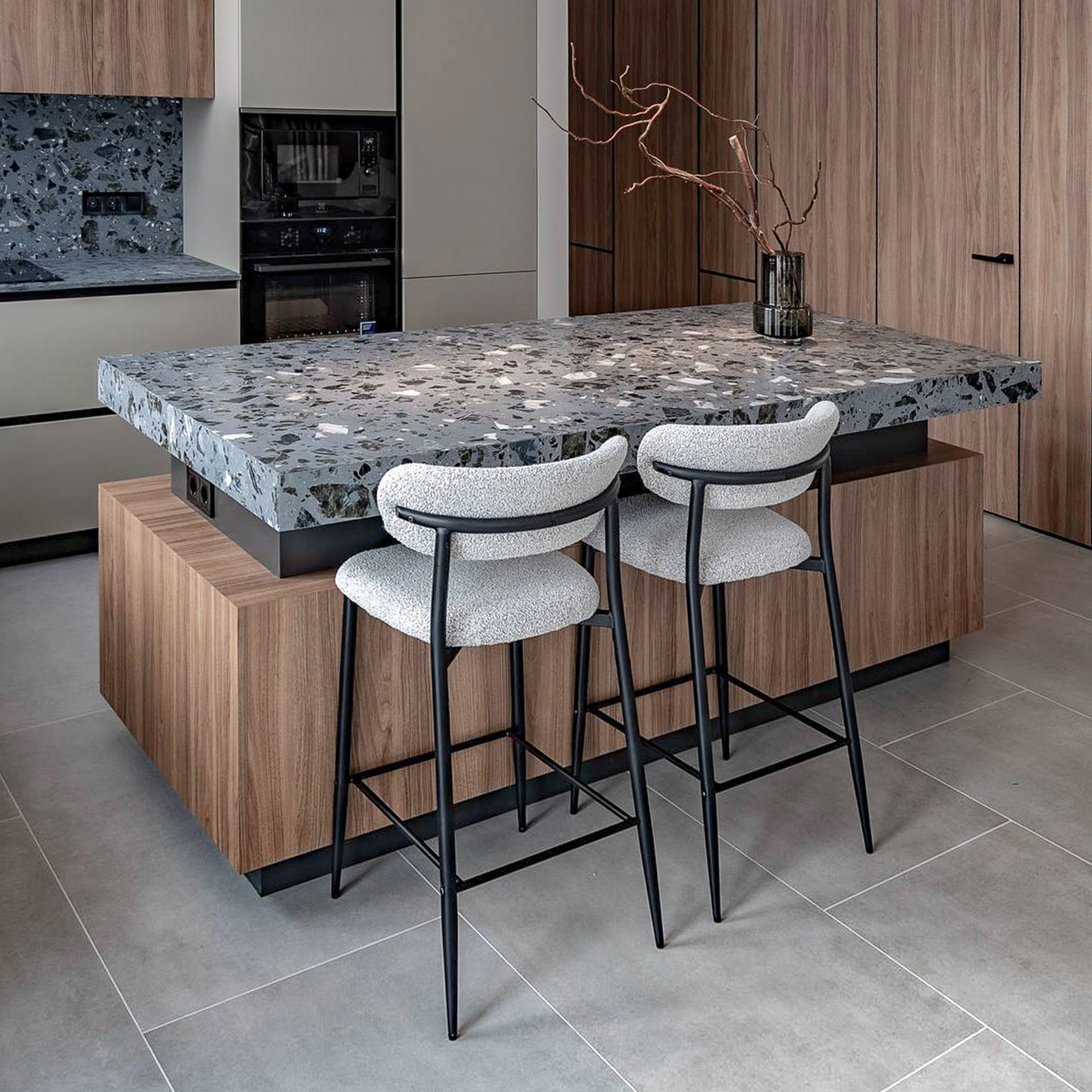Custom terrazzo stone countertop with natural stone aggregate and integrated electrical outlets in a bespoke kitchen interior.