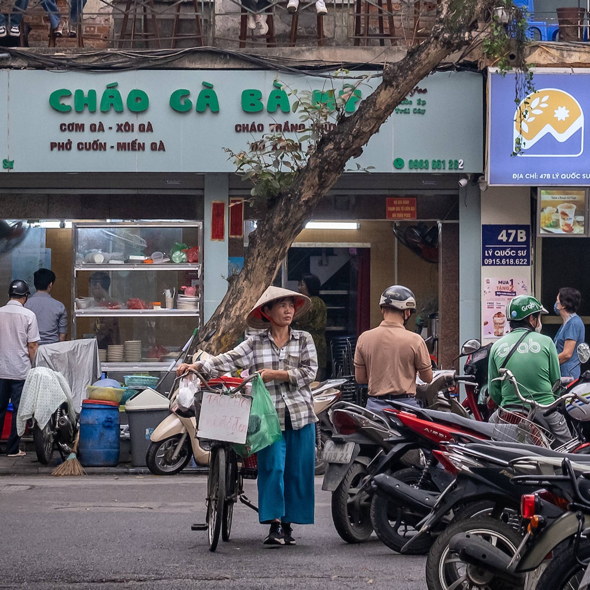 A man stands in the center holding a bicycle on a street in Vietnam