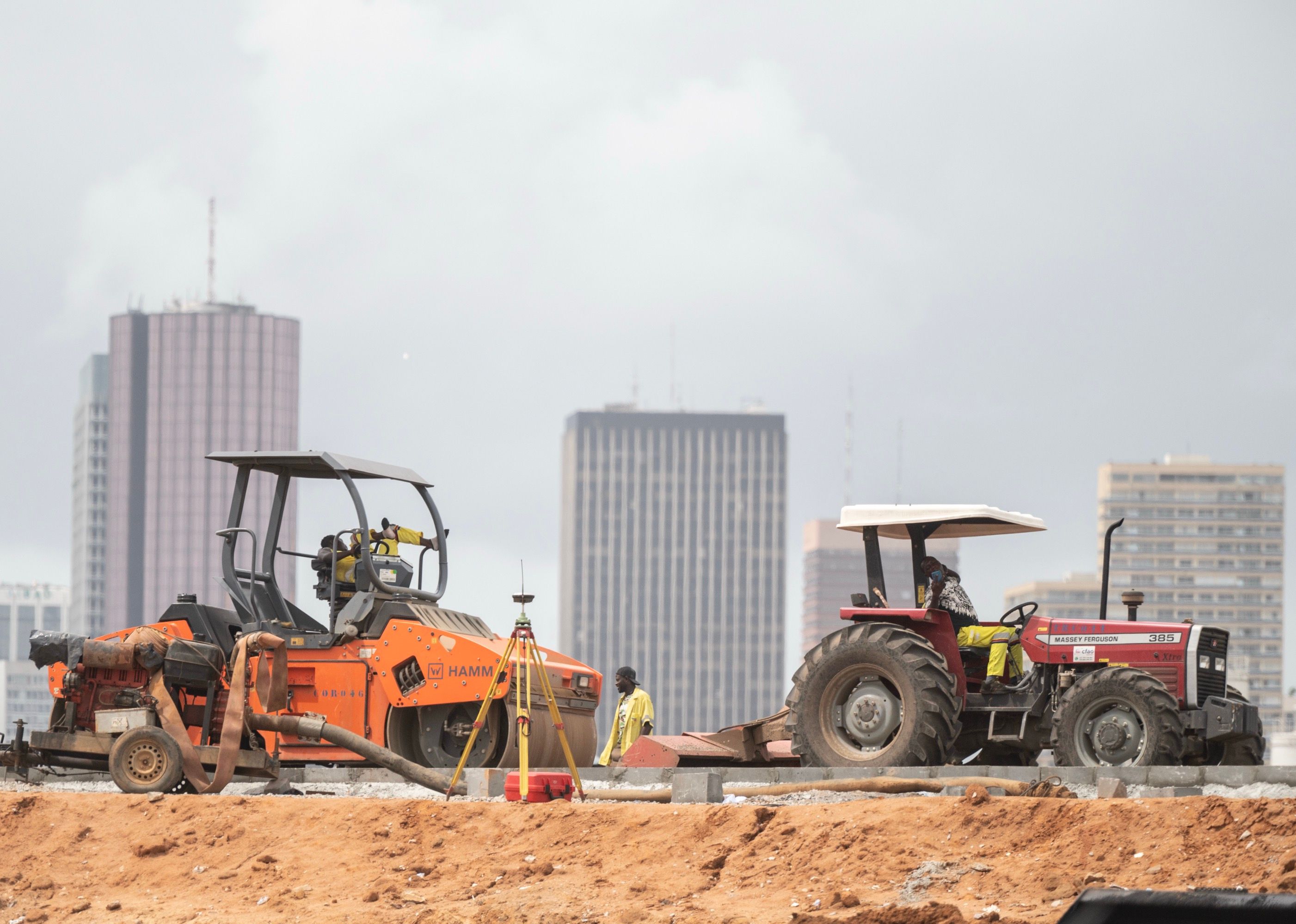A bustling construction site with heavy machinery, workers, and materials scattered across the area.
