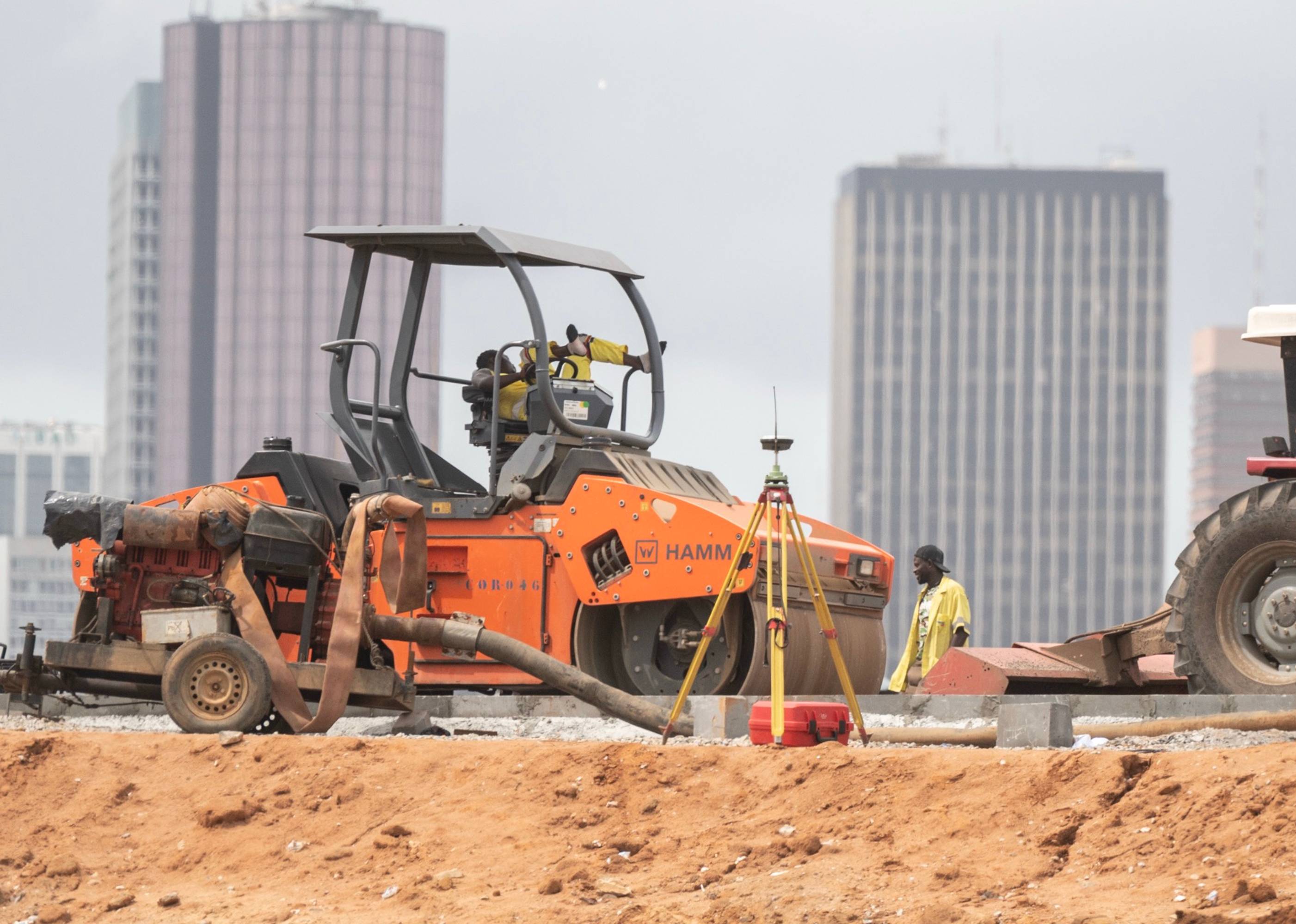A bustling construction site with heavy machinery, workers, and materials scattered across the area.