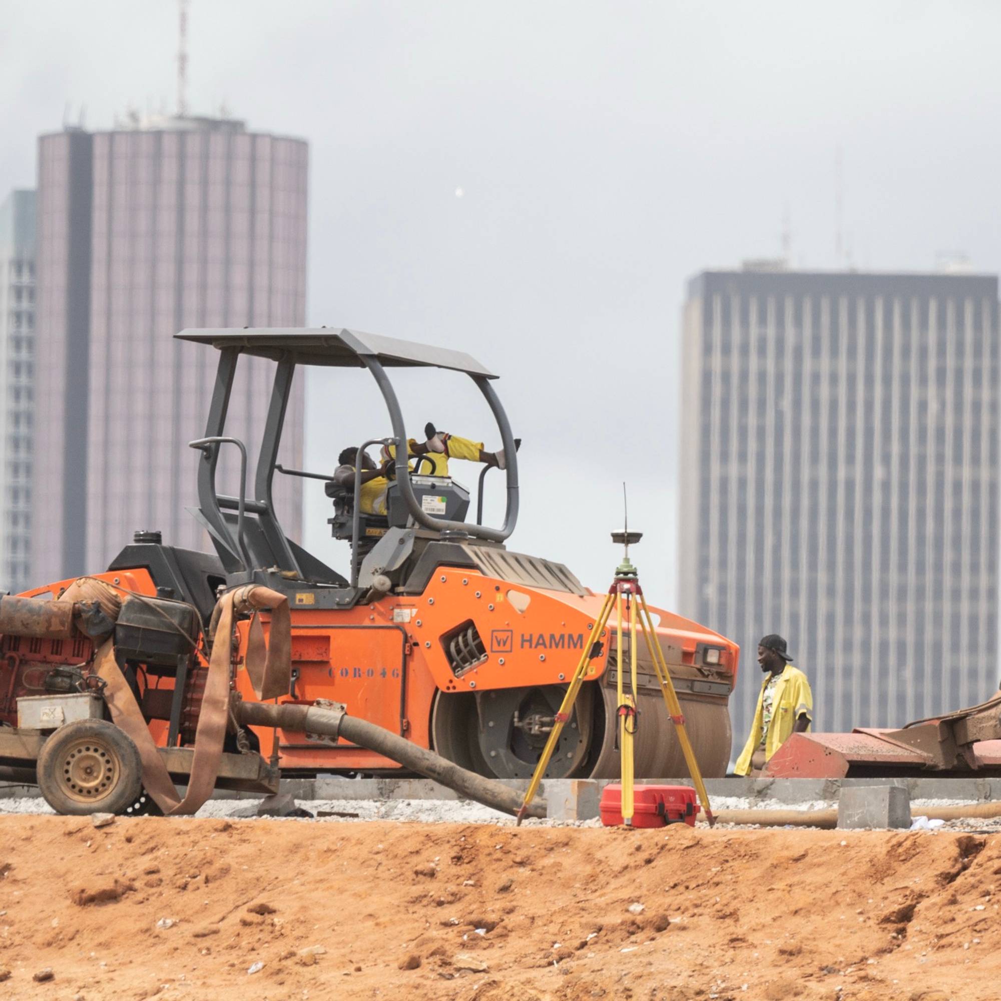 A bustling construction site with heavy machinery, workers, and materials scattered across the area.