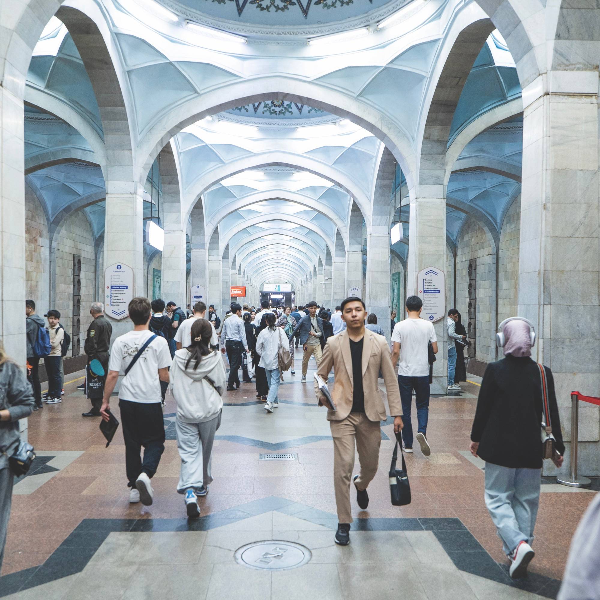 Several individuals walking in a large building's corridor, showcasing a modern architectural design.