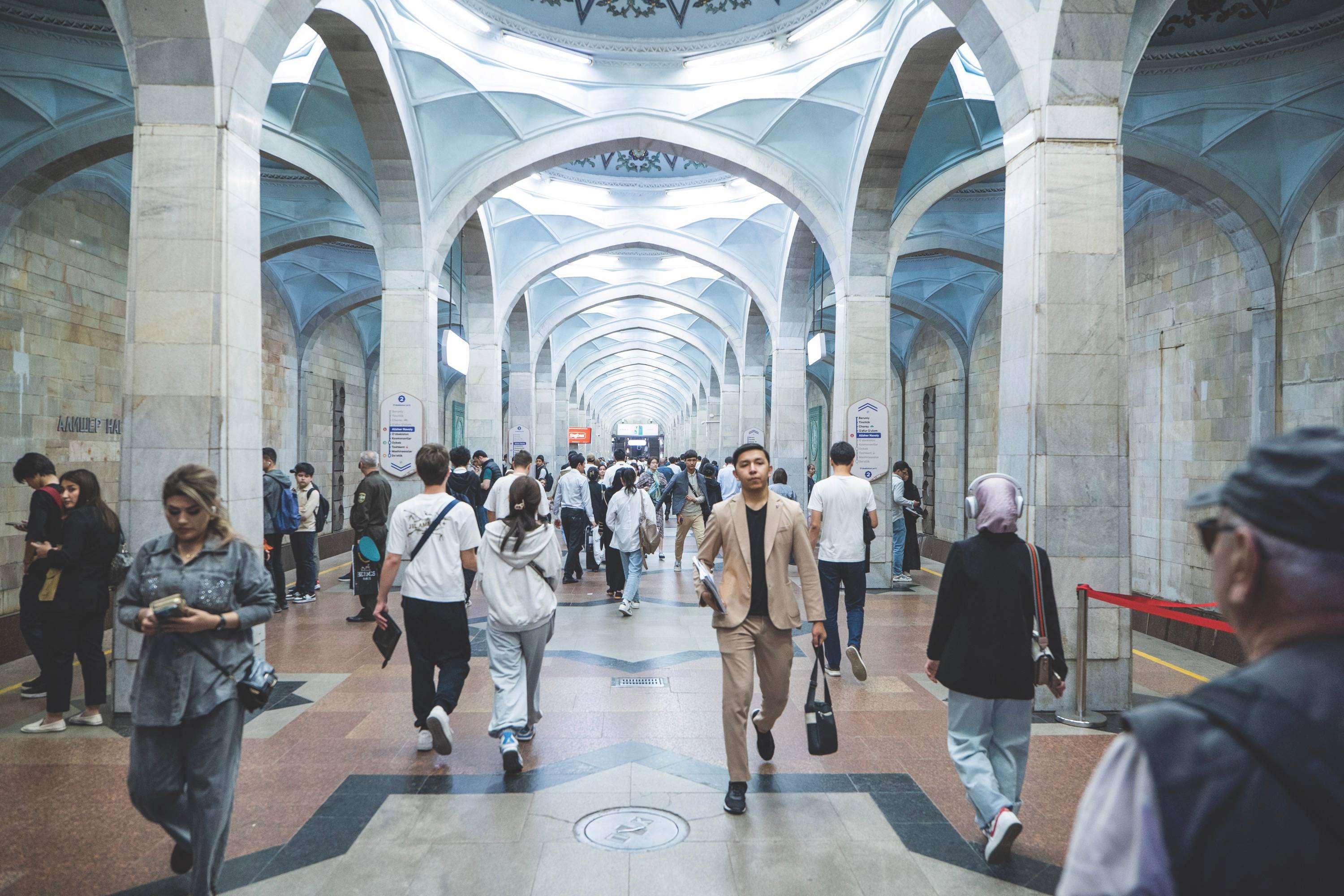 Several individuals walking in a large building's corridor, showcasing a modern architectural design.