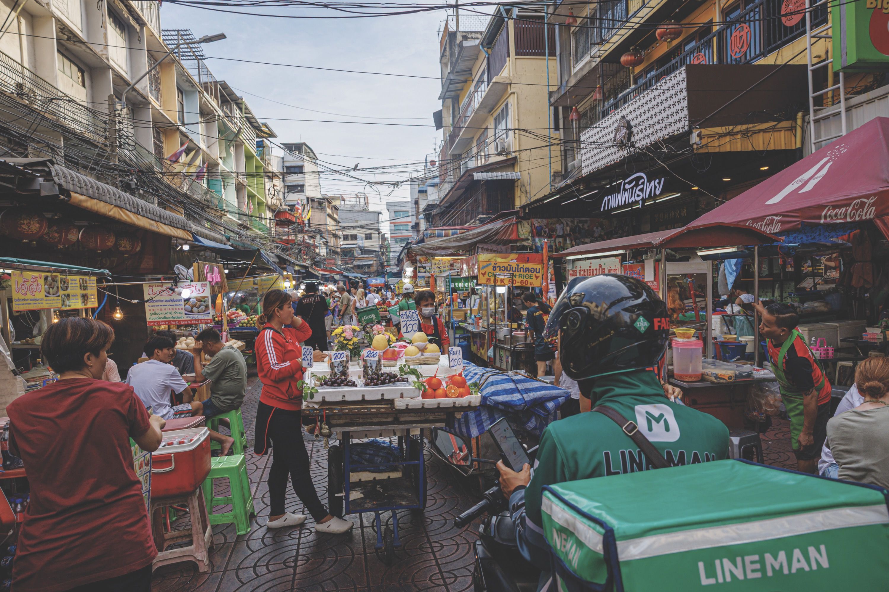Busy street market with fruit stalls and people shopping