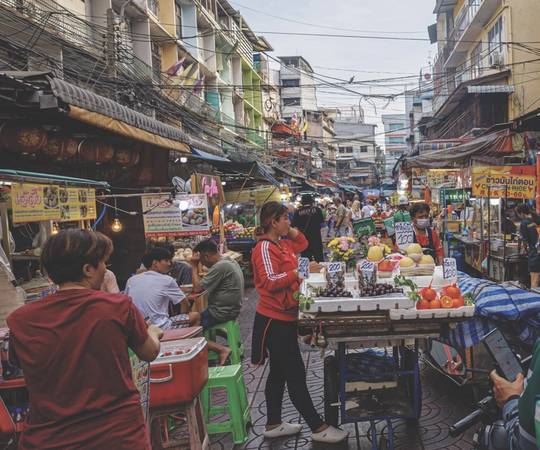 Busy street market with fruit stalls and people shopping