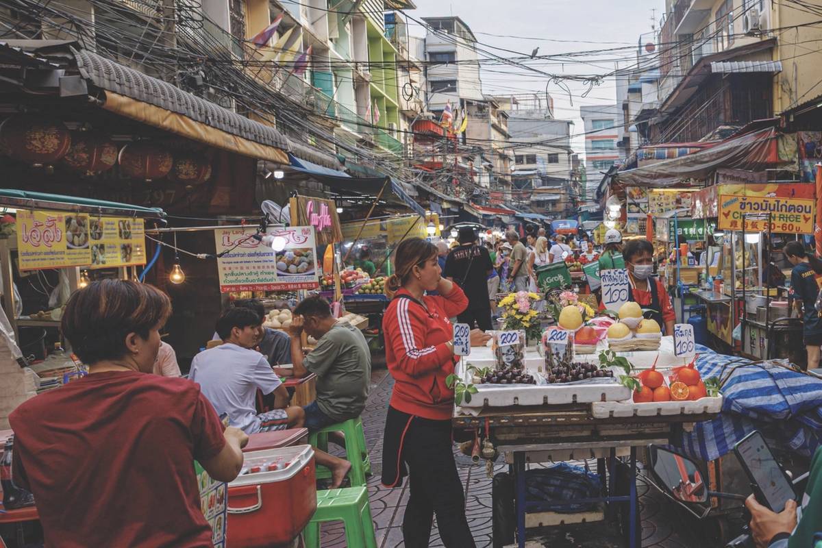 Busy street market with fruit stalls and people shopping