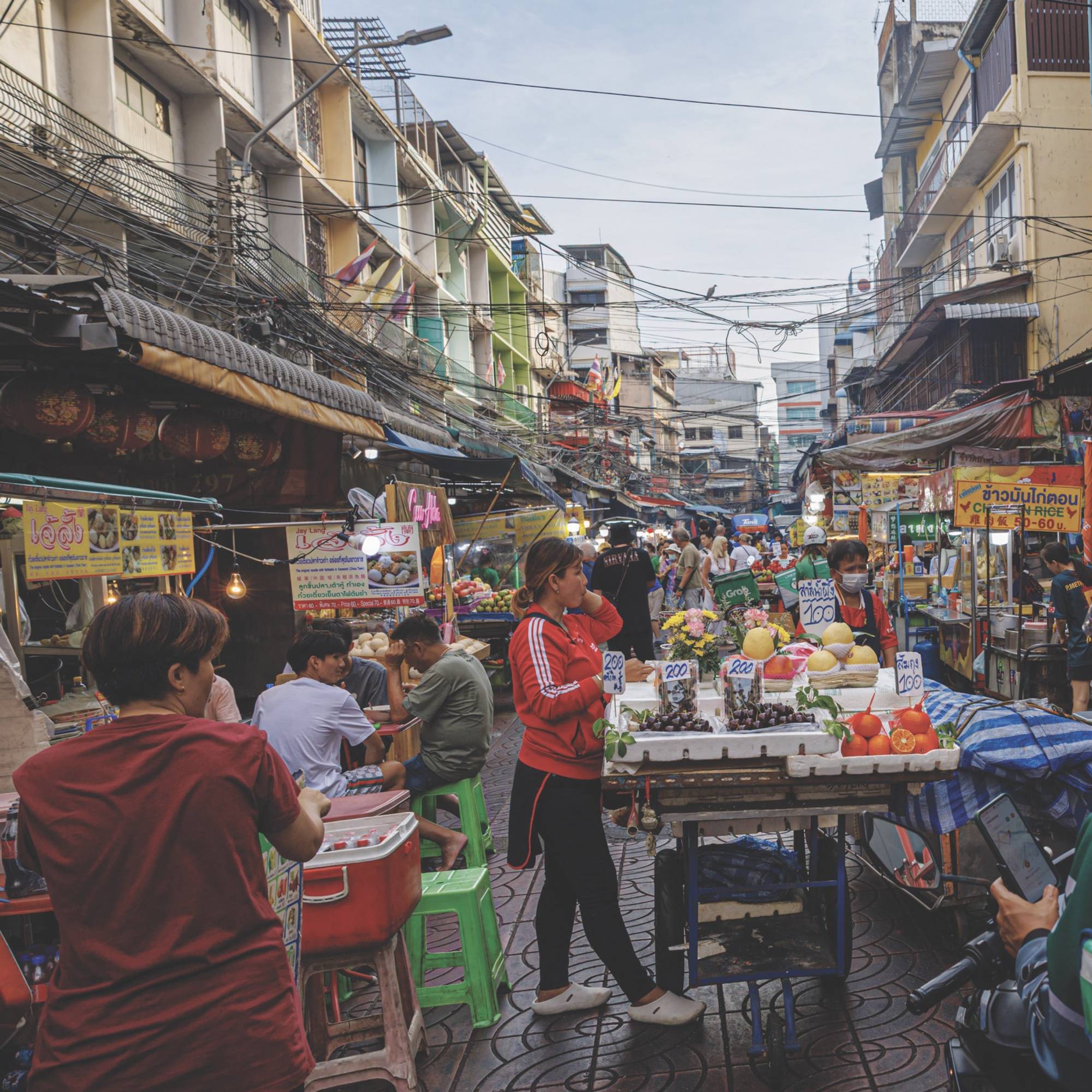Busy street market with fruit stalls and people shopping