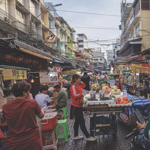 Busy street market with fruit stalls and people shopping