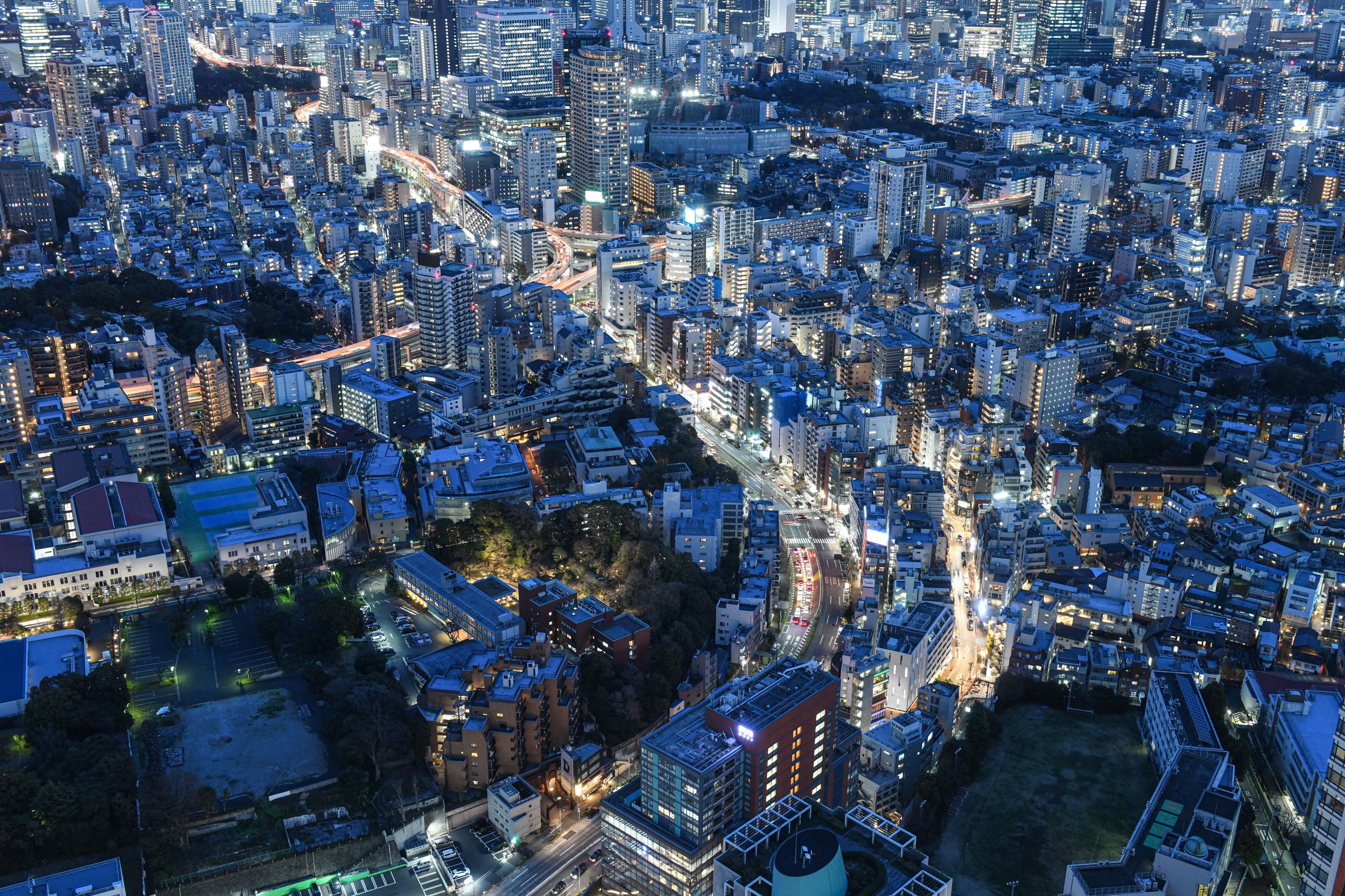 An aerial view of Japan showing many high rise buildings at night with a blue tone