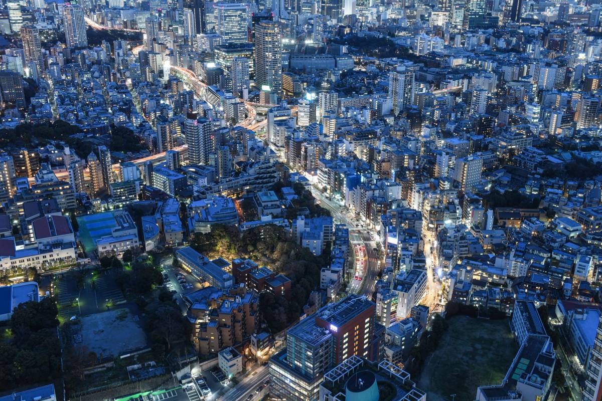 An aerial view of Japan showing many high rise buildings at night with a blue tone