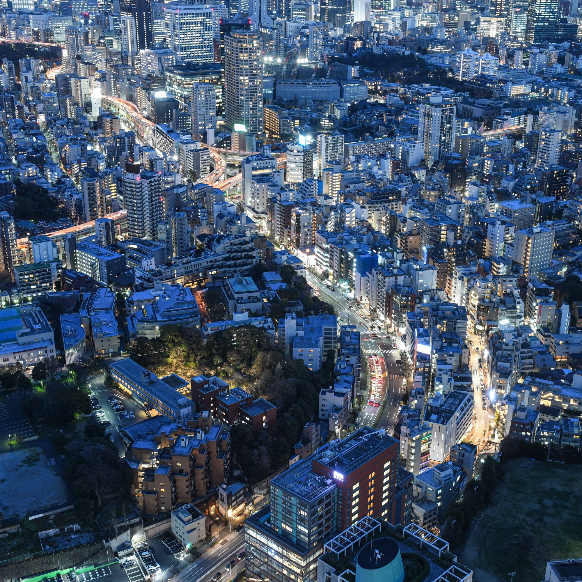 An aerial view of Japan showing many high rise buildings at night with a blue tone