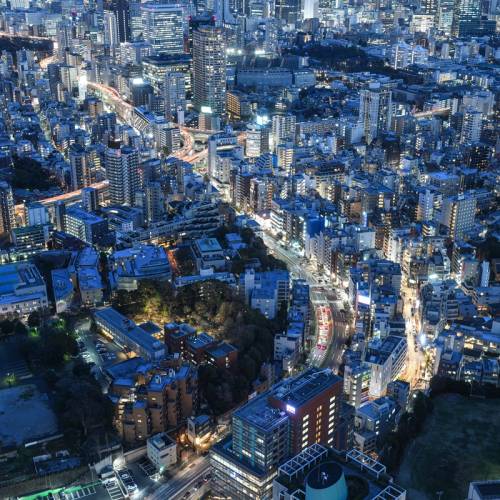 An aerial view of Japan showing many high rise buildings at night with a blue tone