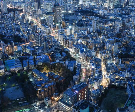 An aerial view of Japan showing many high rise buildings at night with a blue tone