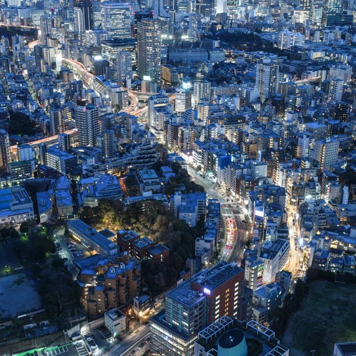 An aerial view of Japan showing many high rise buildings at night with a blue tone