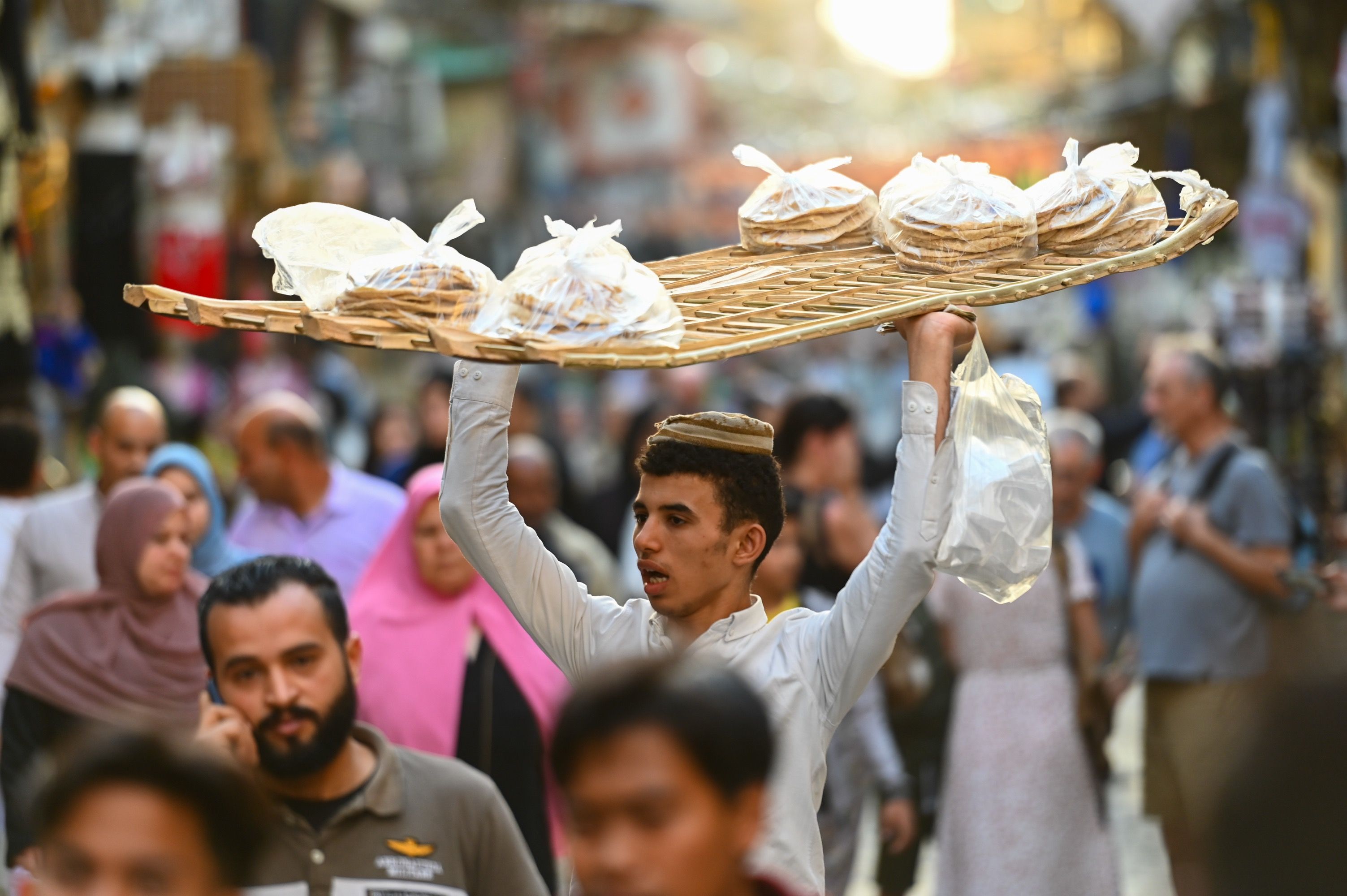 A man carries a large trey over his head balancing food on top of it
