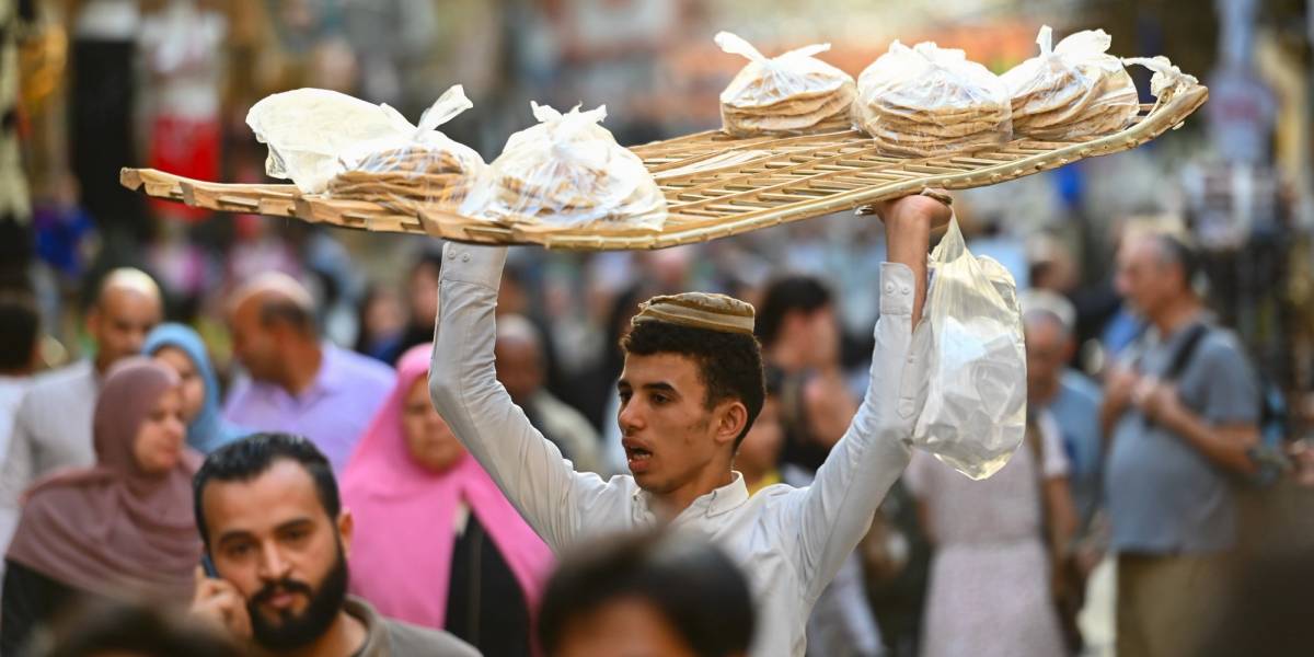 A man carries a large trey over his head balancing food on top of it