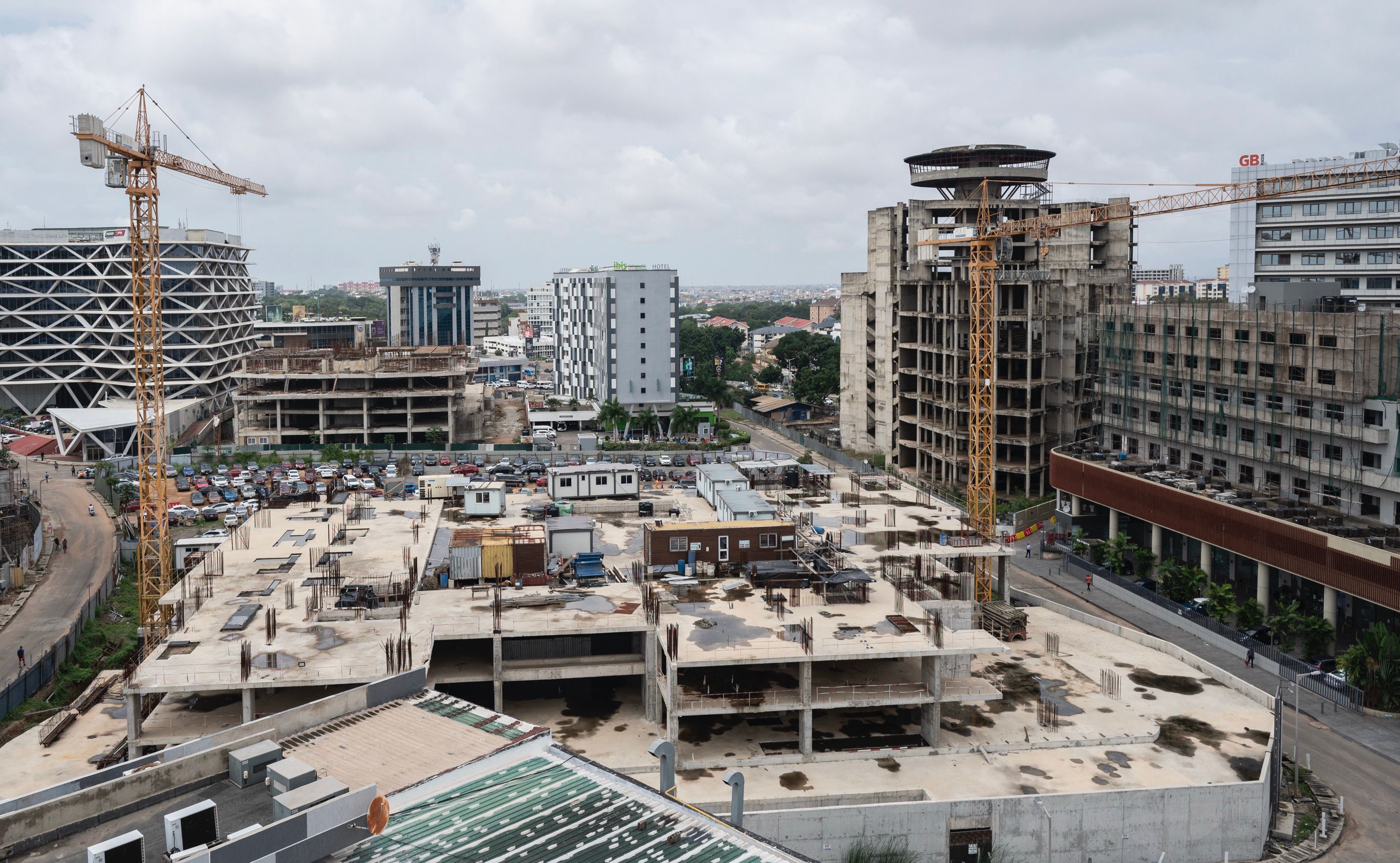 A cityscape of buildings under construction with two cranes visible