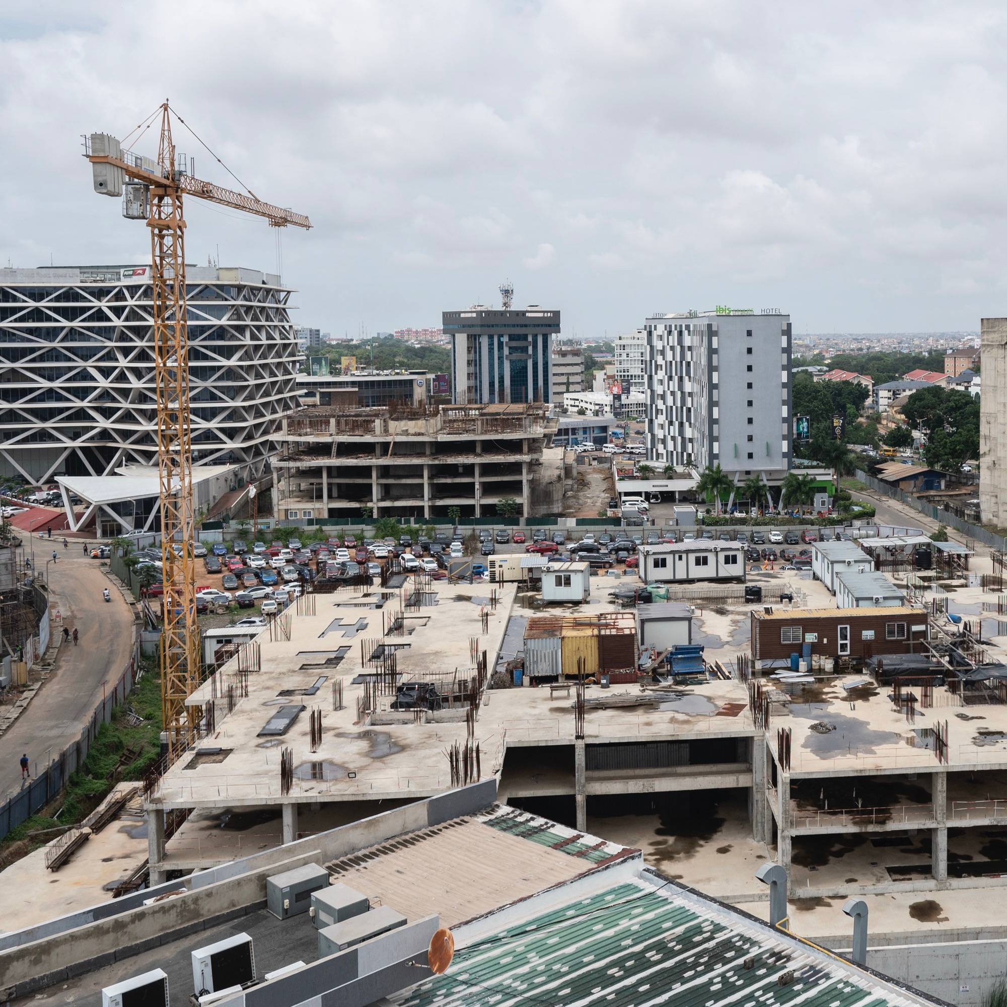 A cityscape of buildings under construction with two cranes visible