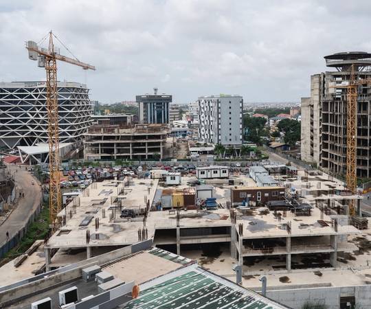 A cityscape of buildings under construction with two cranes visible