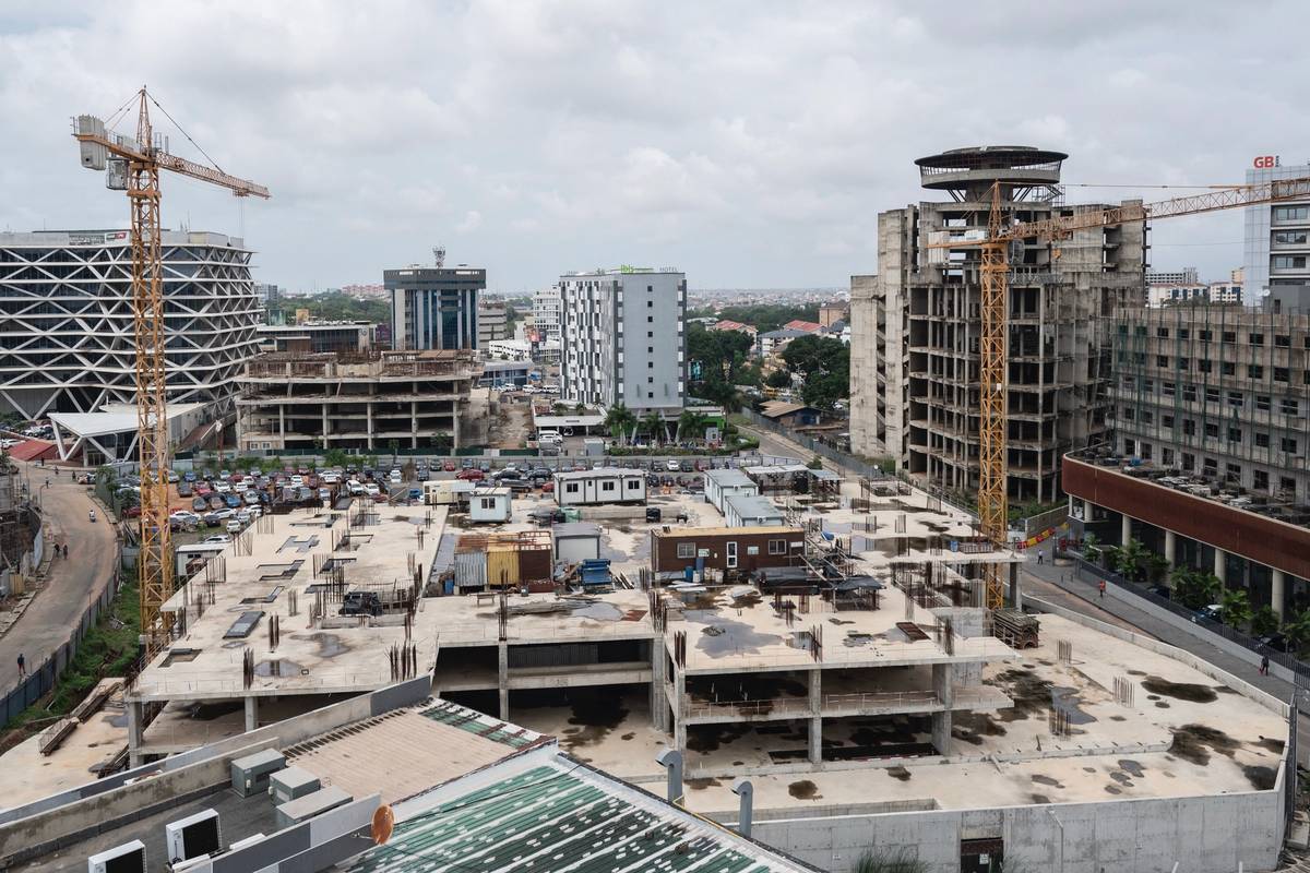 A cityscape of buildings under construction with two cranes visible