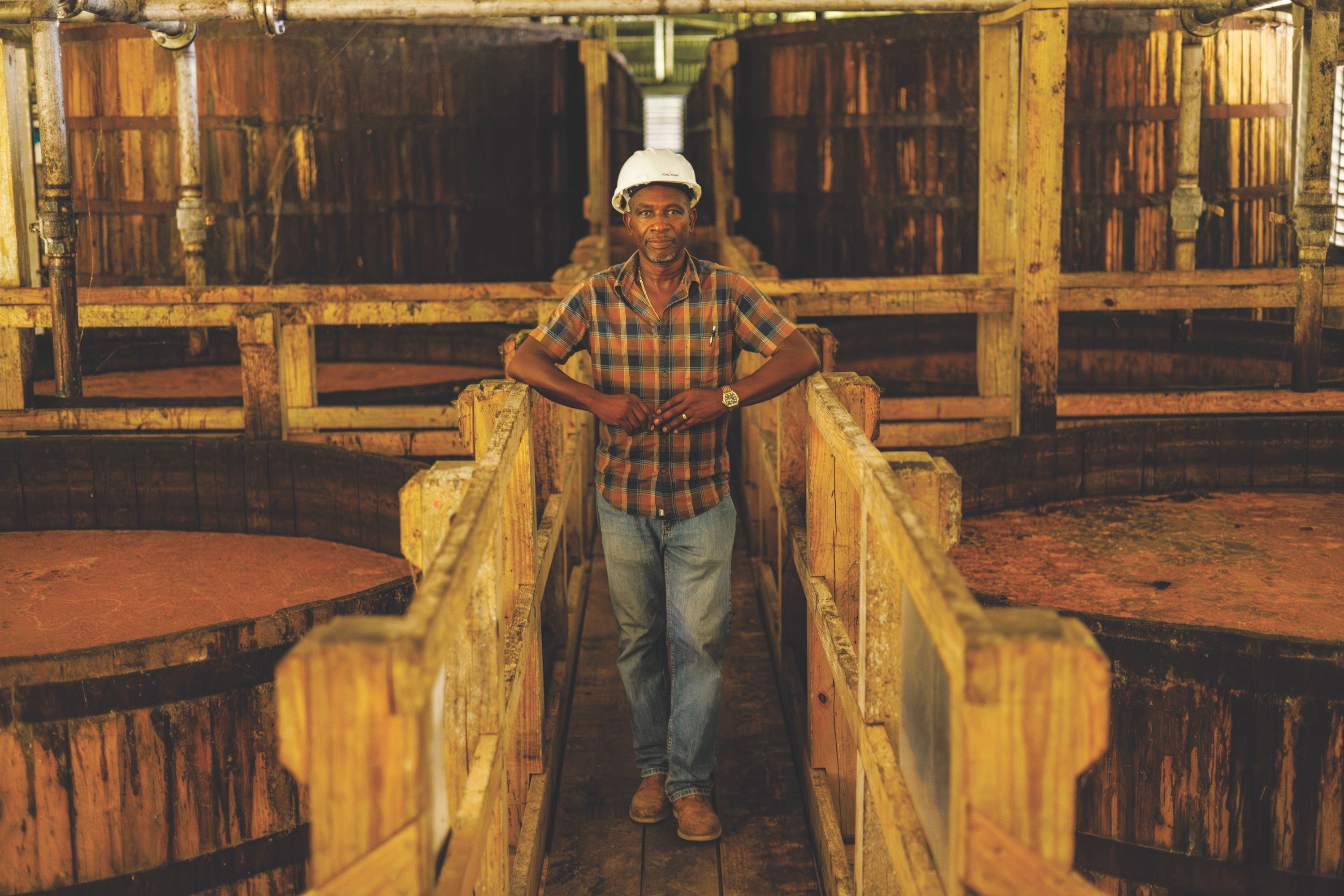 A man stands next to large wooden barrels, smiling and looking out at the camera.
