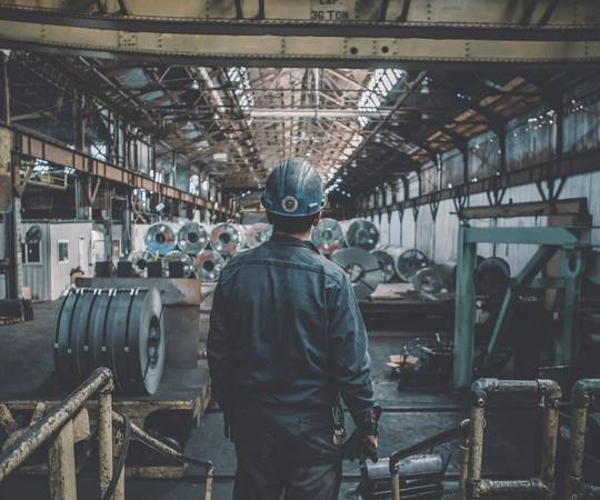 Worker in a hard hat inside a steel factory