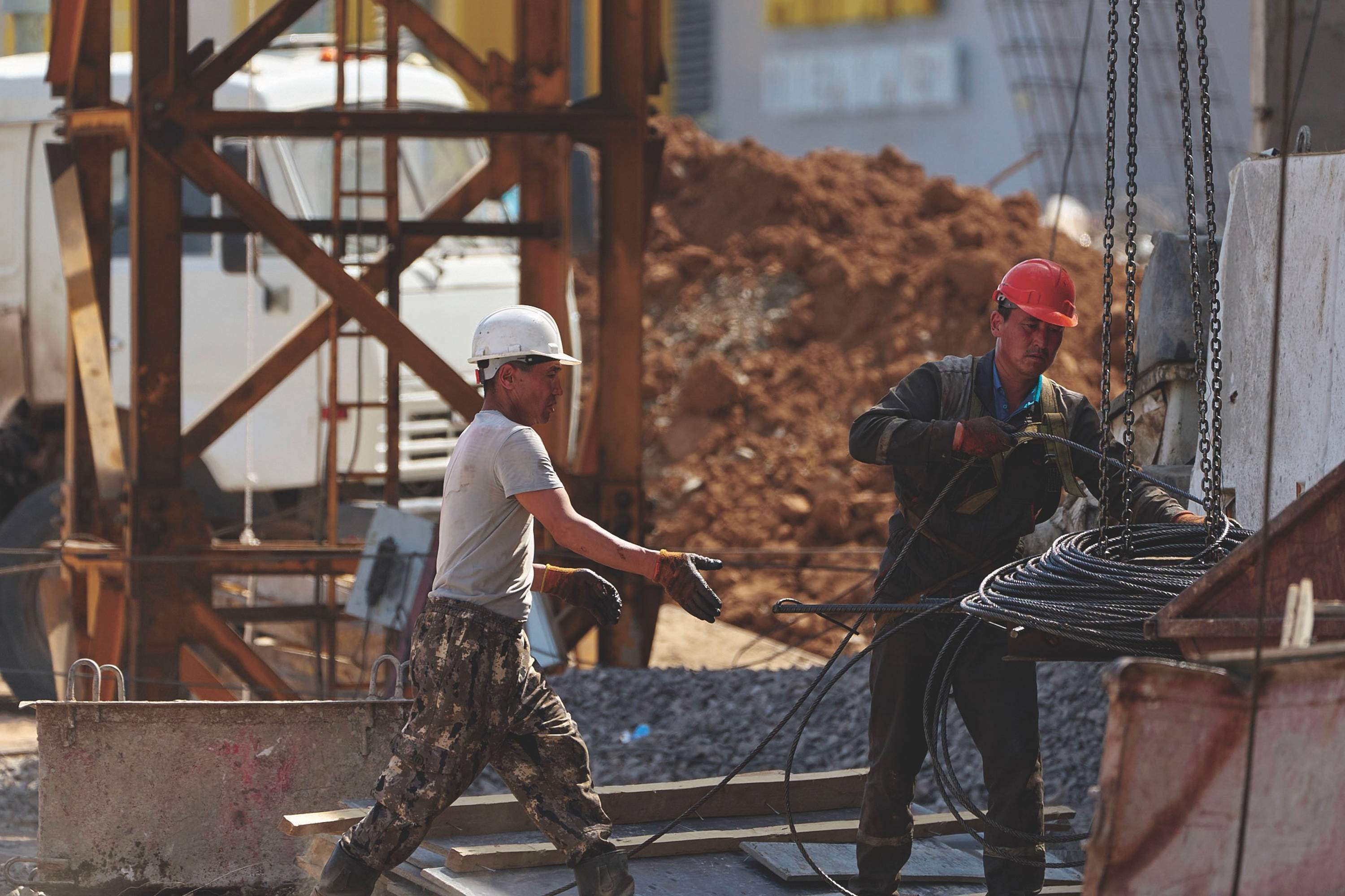 Two men wearing hard hats working in a construction area