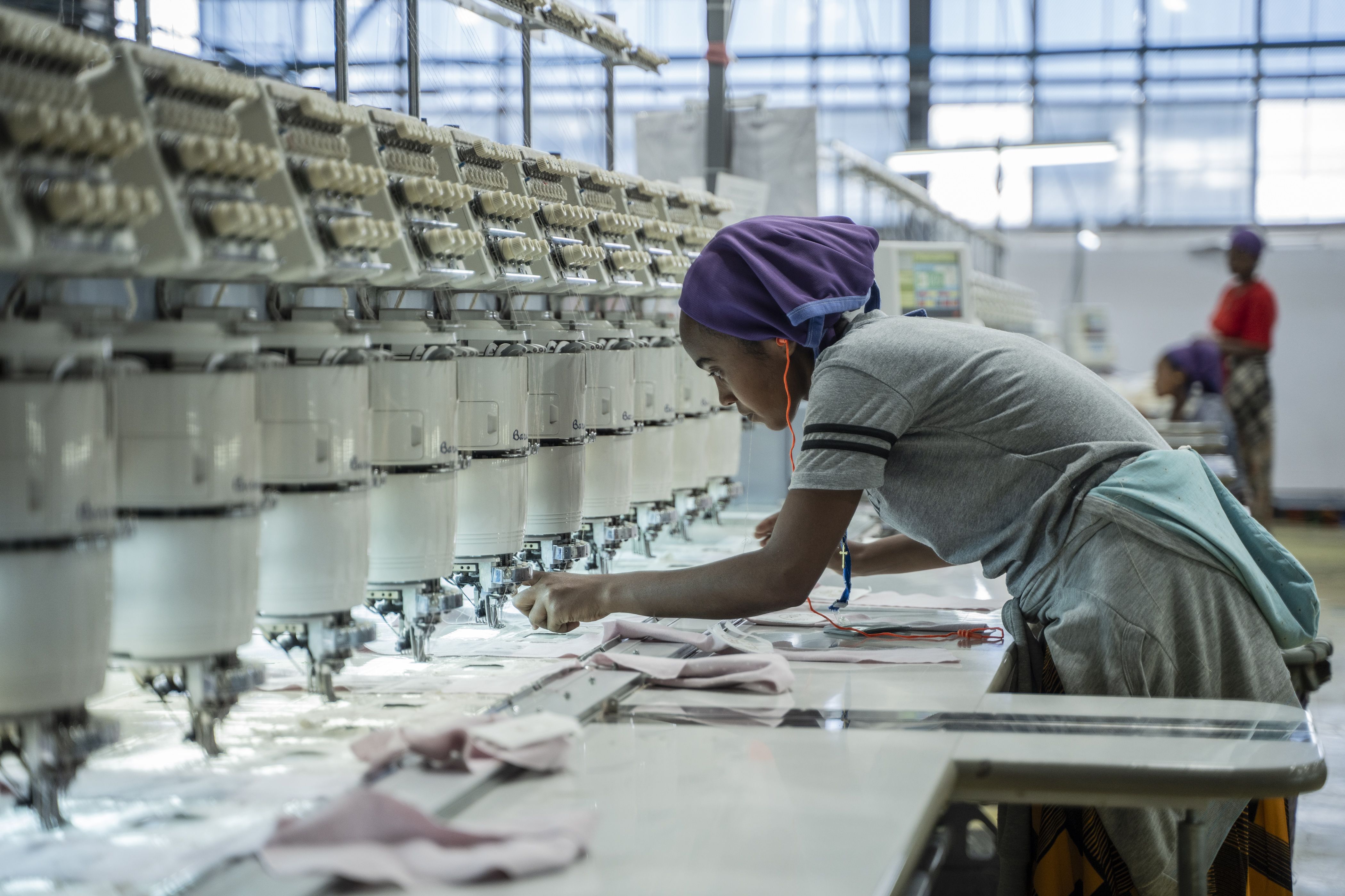 A woman works on a machine at a textile factory