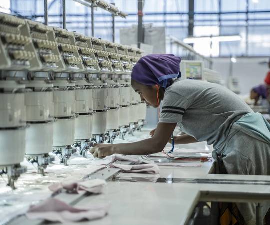 A woman works on a machine at a textile factory