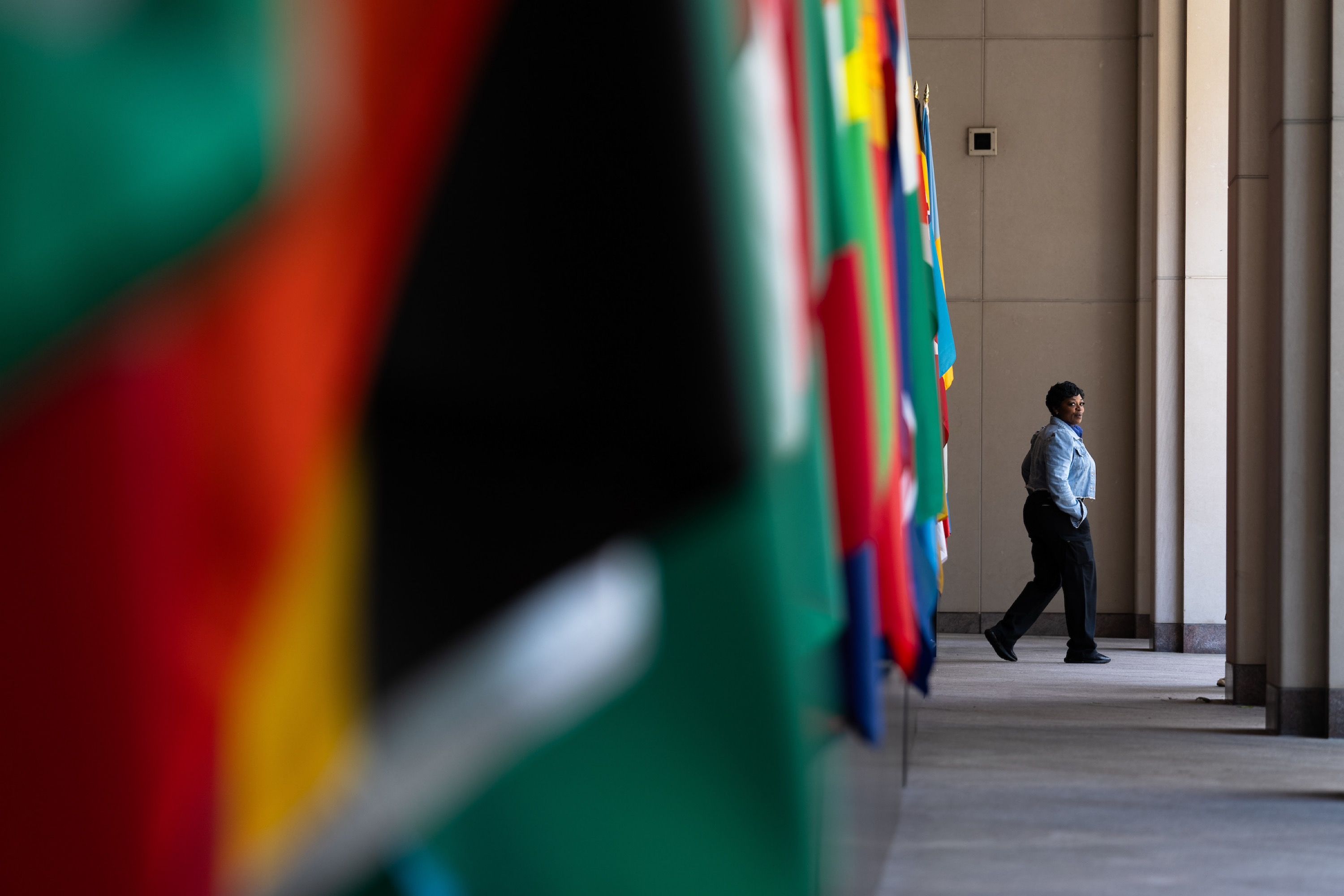 A security woman walks towards the outside with flags of the world in the foreground
