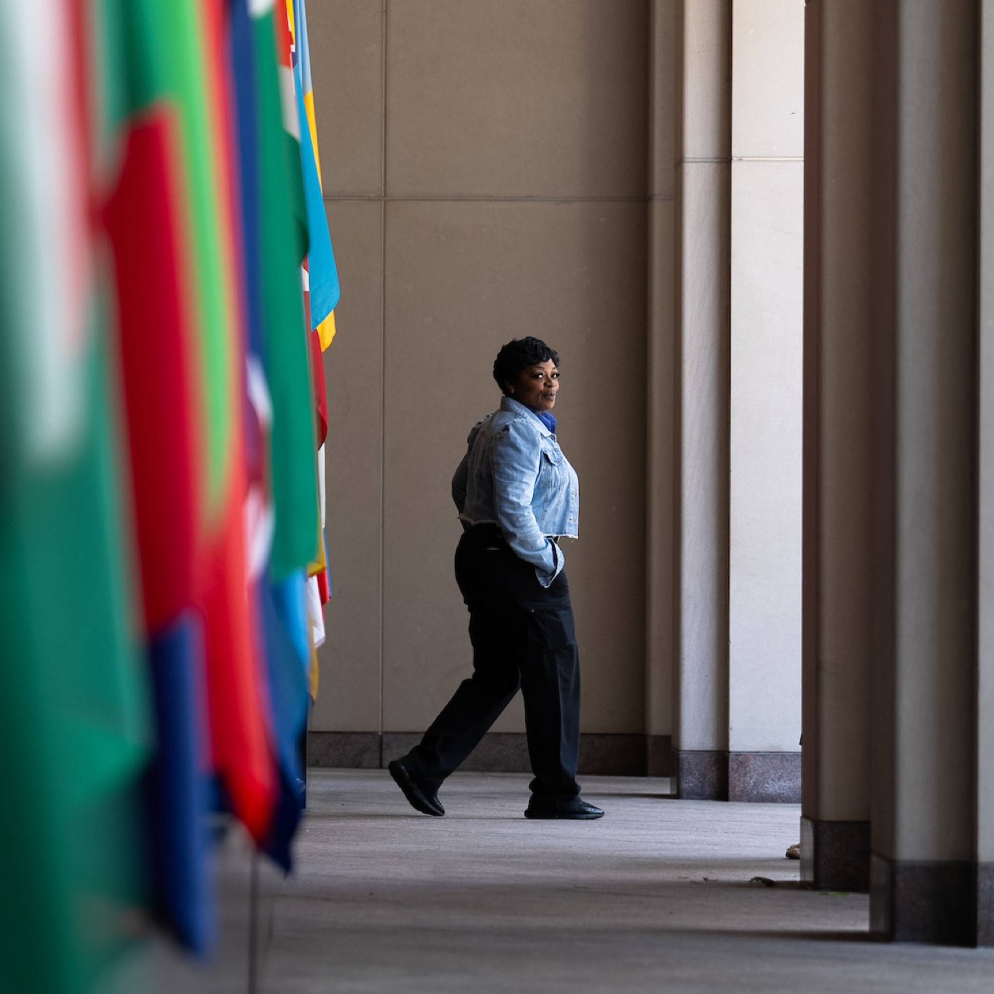 A security woman walks towards the outside with flags of the world in the foreground