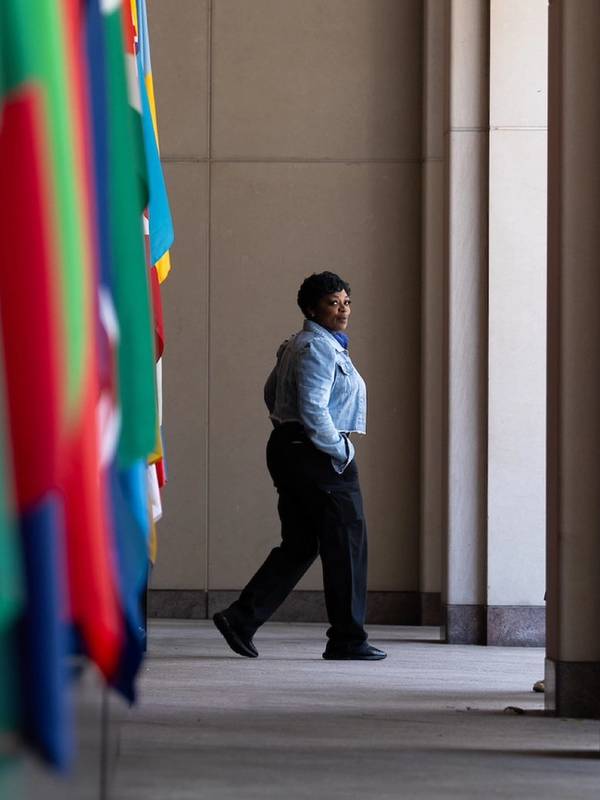 A security woman walks towards the outside with flags of the world in the foreground