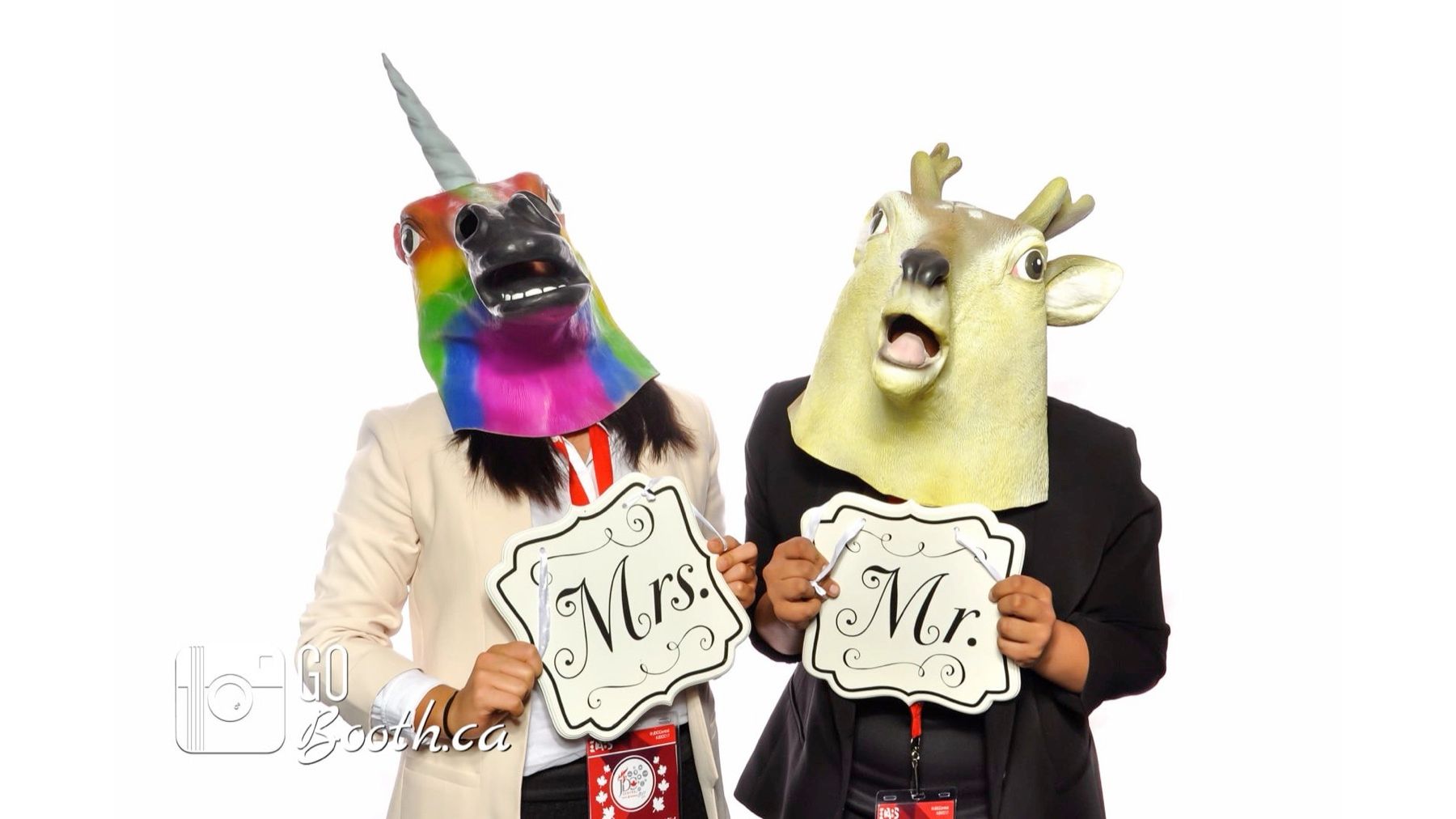 Two guests in animal masks holding hand-cut “Mrs.” and “Mr.” sign props