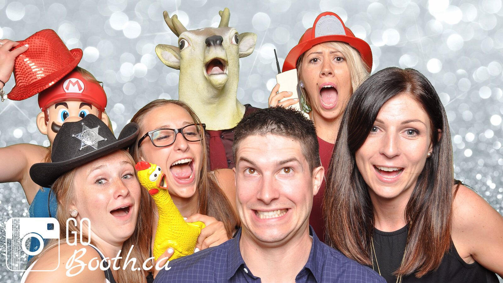 Group of friends with props in front of a silver sequin backdrop