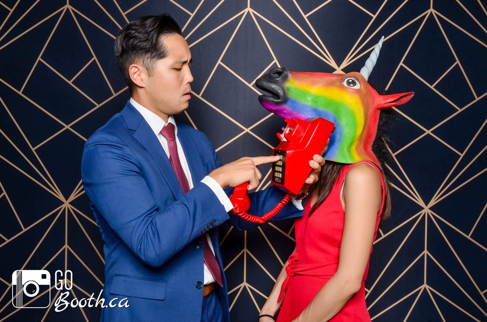Guest in a rainbow unicorn mask taking a call on a vintage red phone