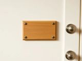 Plaque en bois clair vissée sur une porte de chambre d'hôtel