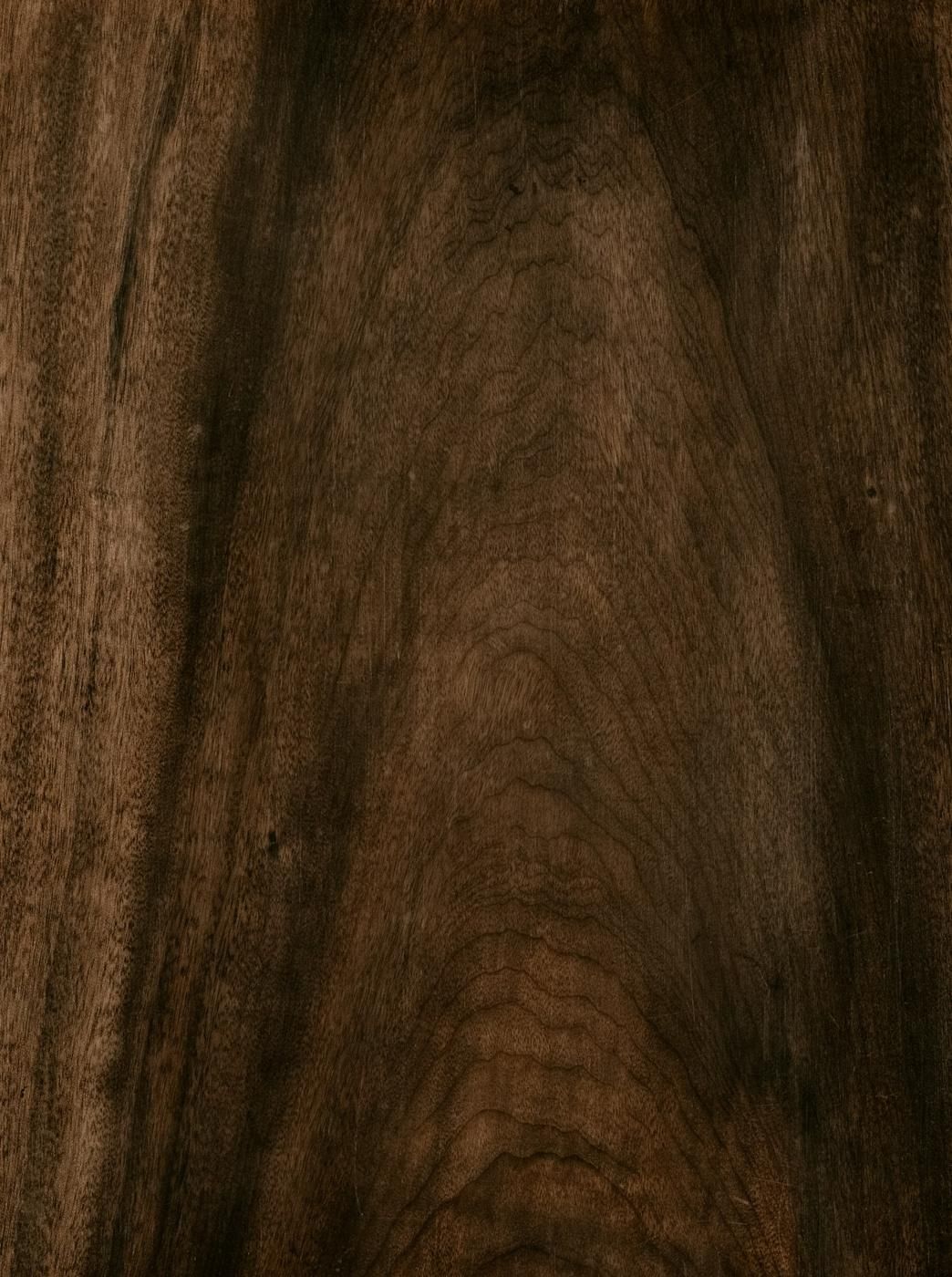 Gros plan sur le veinage d'un bois sombre de type noyer (photo Unsplash provisoire)