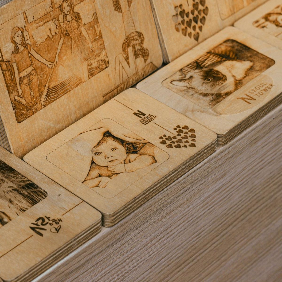 Plaquettes en bois clair gravées au laser de portraits et de motifs (photo Unsplash provisoire)