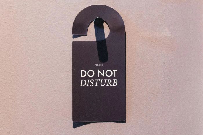 Affichette de porte « Do not disturb » noire suspendue sur un mur rose pâle (photo Unsplash provisoire)